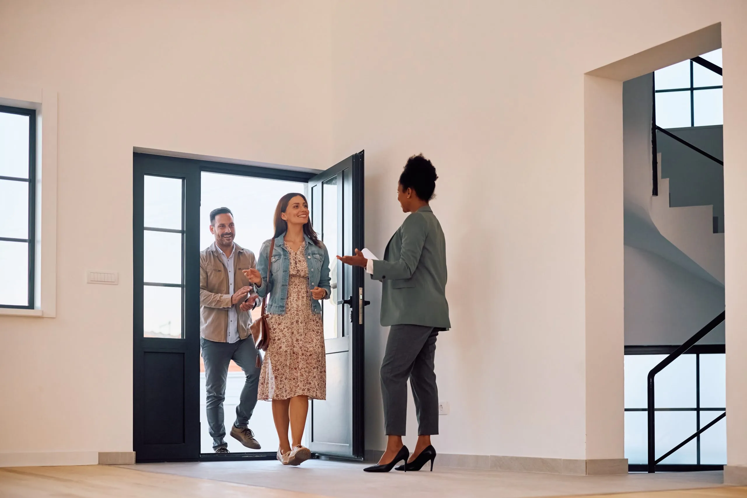 A real-estate agent welcoming a couple into a home