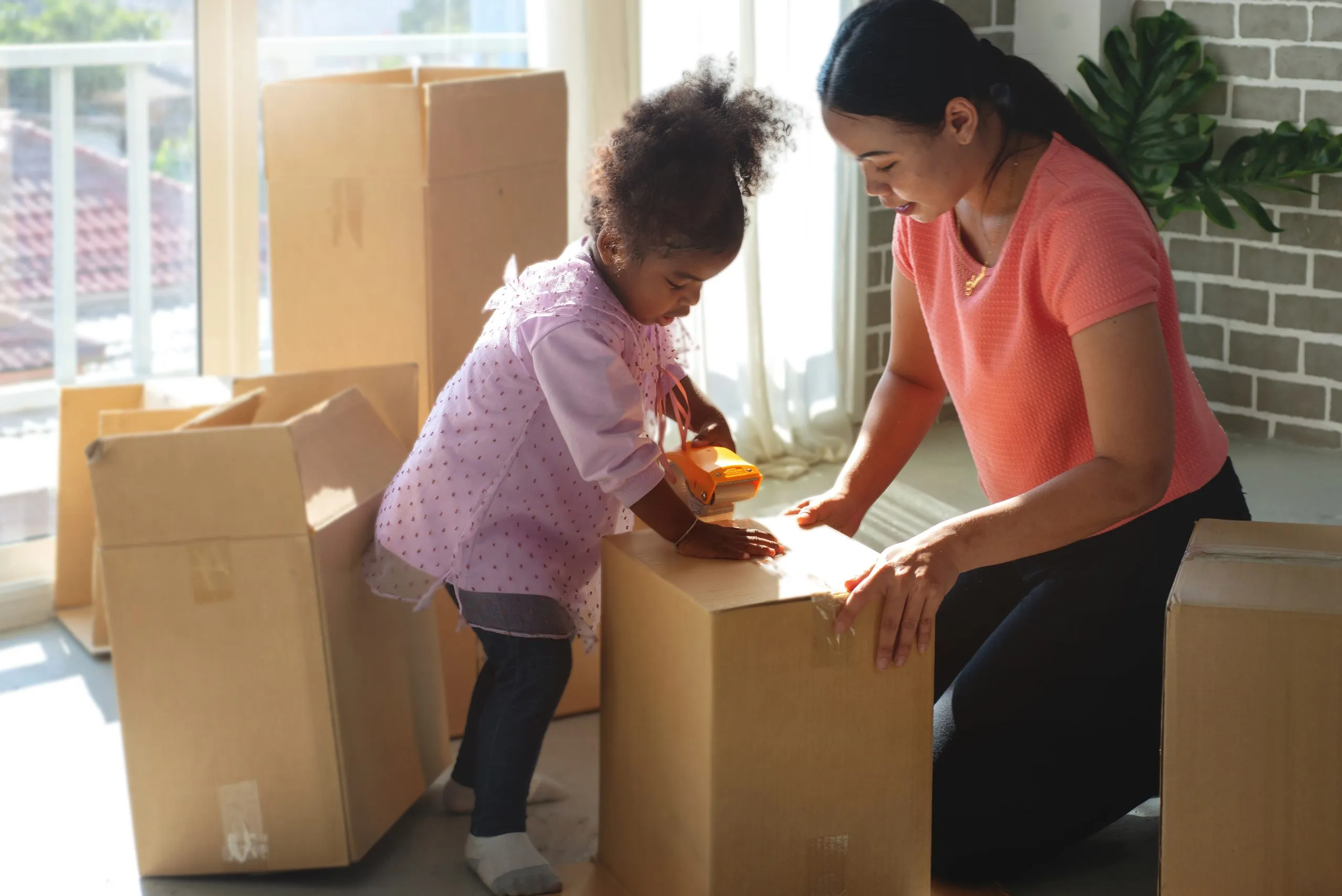 A parent and child packing moving boxes in their home